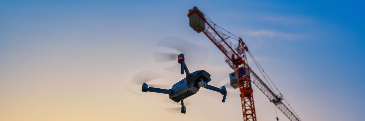 Eine Drohne fliegt durch die Natur Titelbild: Eine Drohne fliegt neben einem Kran